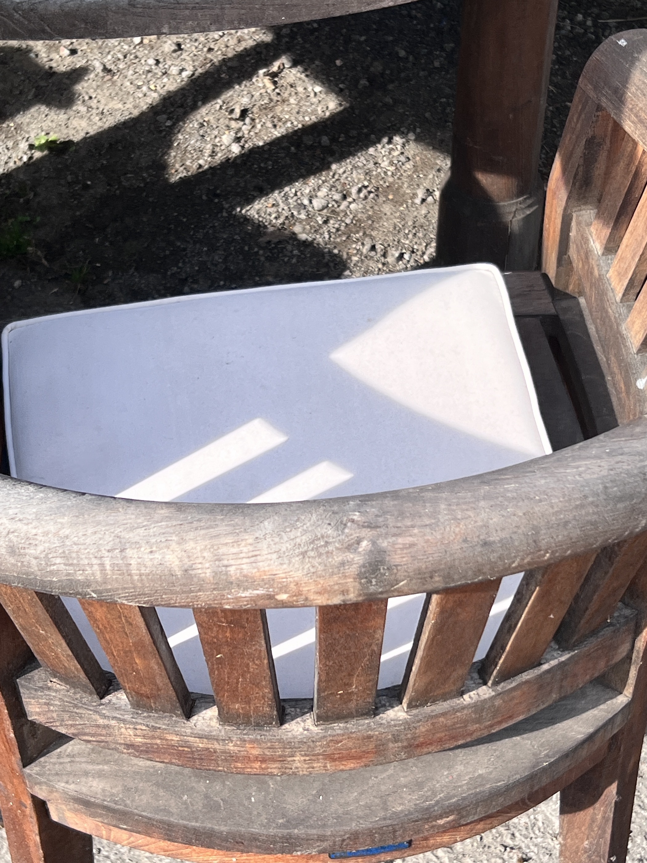 A large circular weathered teak garden table with Lazy Susan, diameter 180cm, height 75cm, together with six tub framed chairs with seat cushions